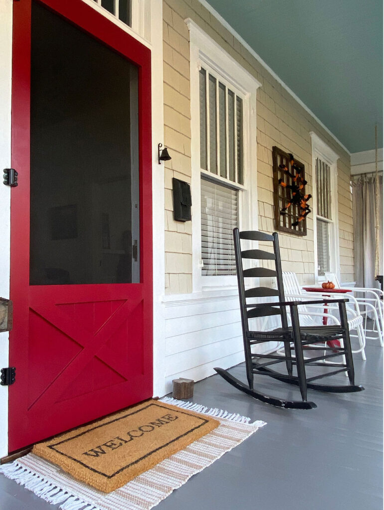 Front porch of historic home with red screen door.