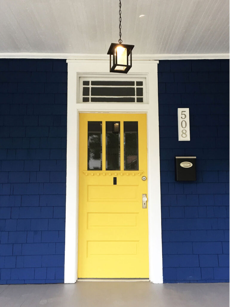 Navy historic home with colorful yellow front door.