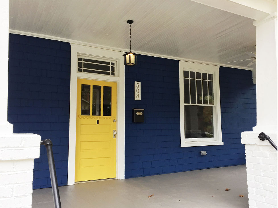 Colorful navy historic home with yellow front door.